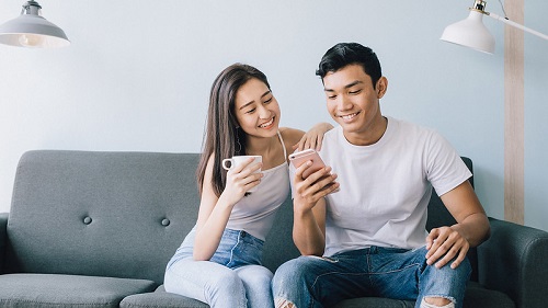 Two people sitting on the couch looking a their phones