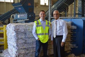 Two men standing in front of a scrap paper bale