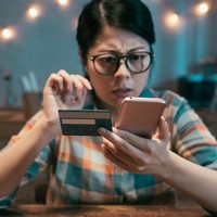 Woman looking at her phone and credit card