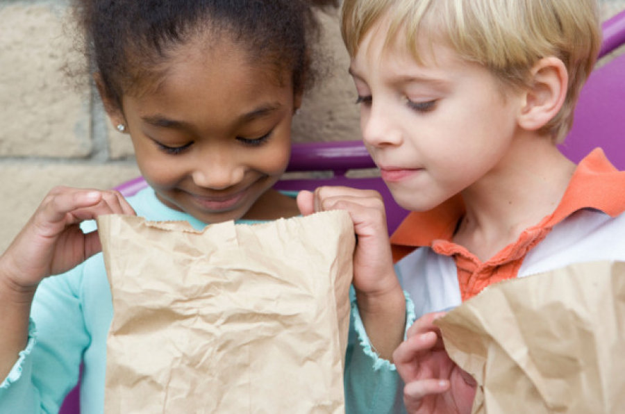 Two kids looking inside of a lunch bag
